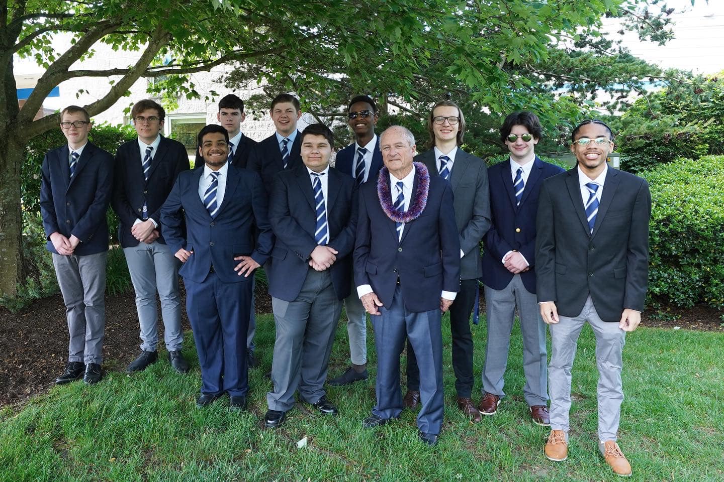 A group of men in suits from a college preparatory school posing for a picture.