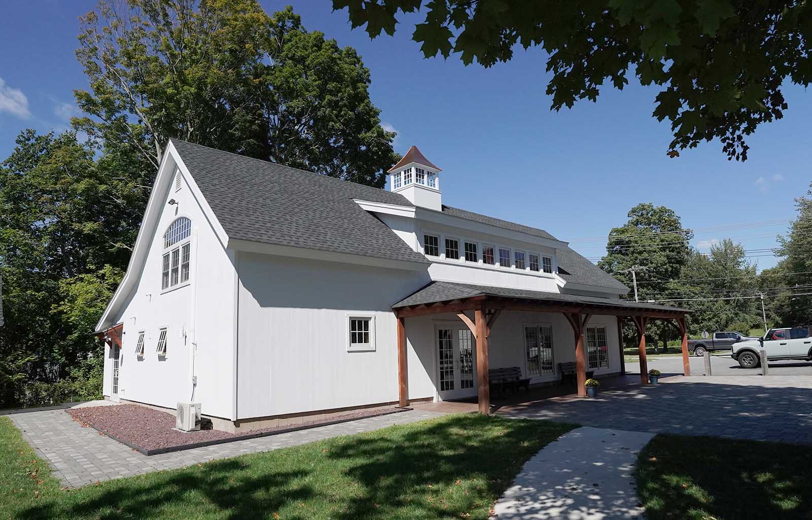 A white house with a porch and a car parked in front of it.