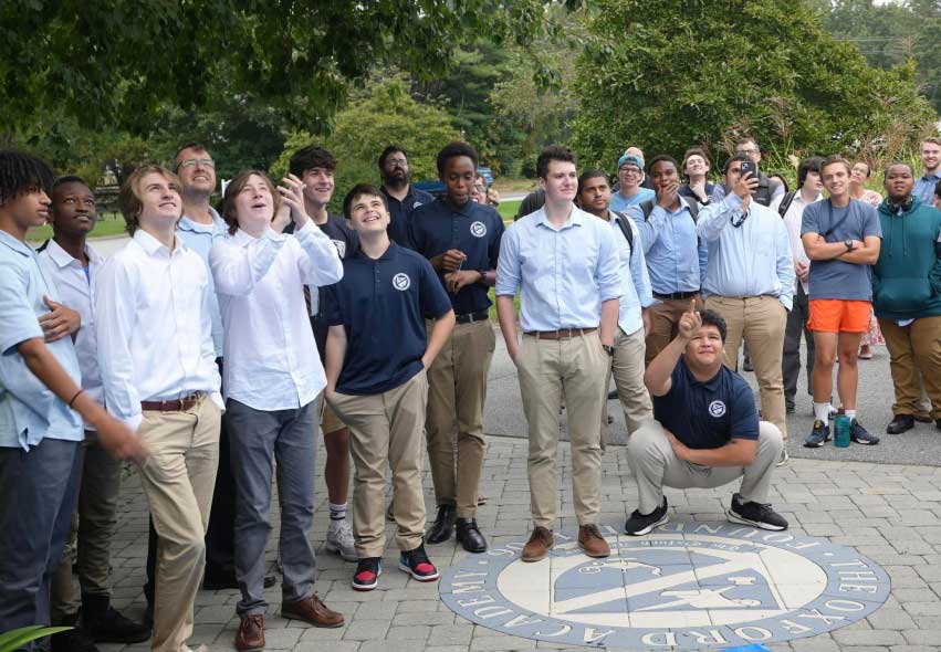 A group of men in blue shirts standing in front of a circle.