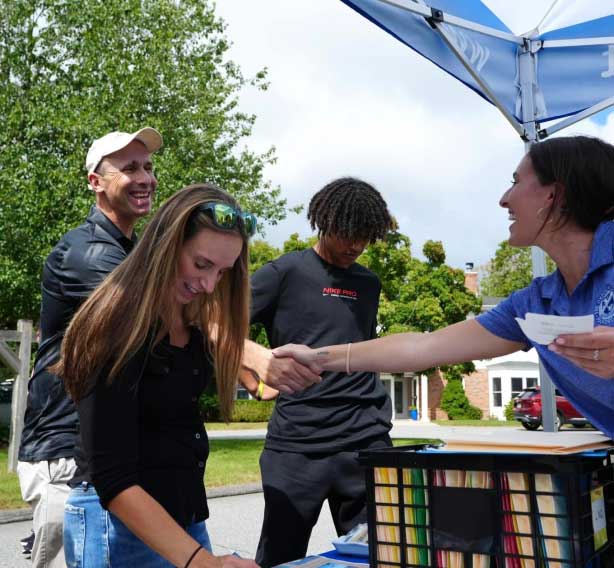 A group of people shaking hands under a blue tent.