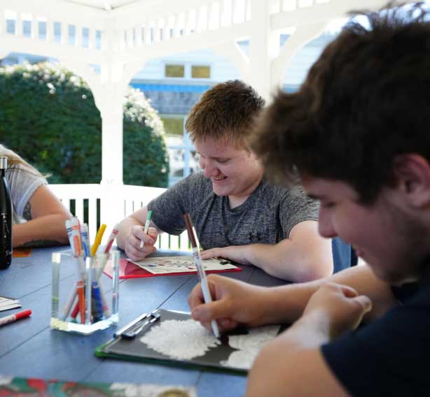 A group of young people sitting at a table with coloring books.