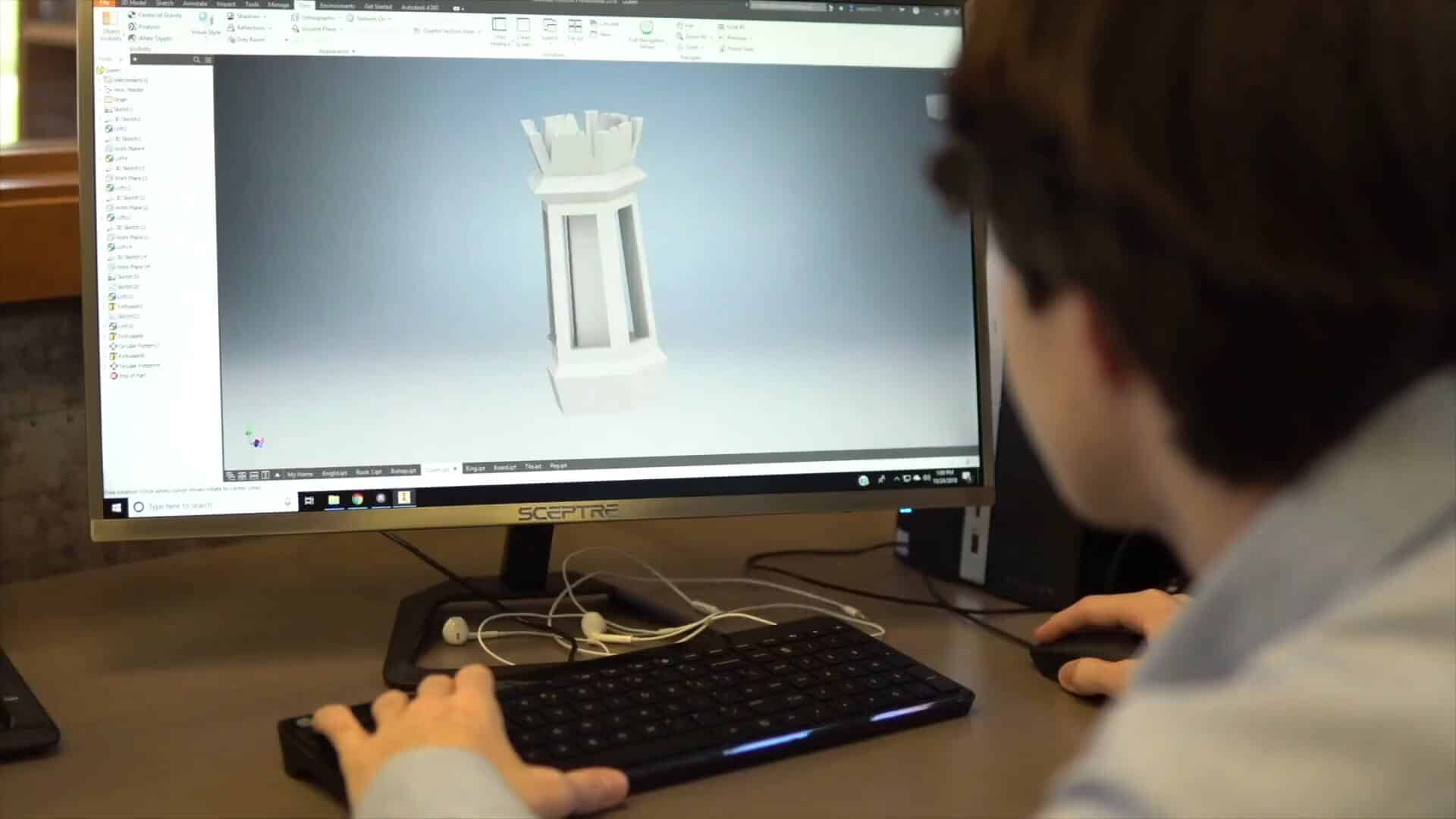 A person enjoys a summer experience using a computer to design a 3D model of a rook chess piece displayed on the monitor.